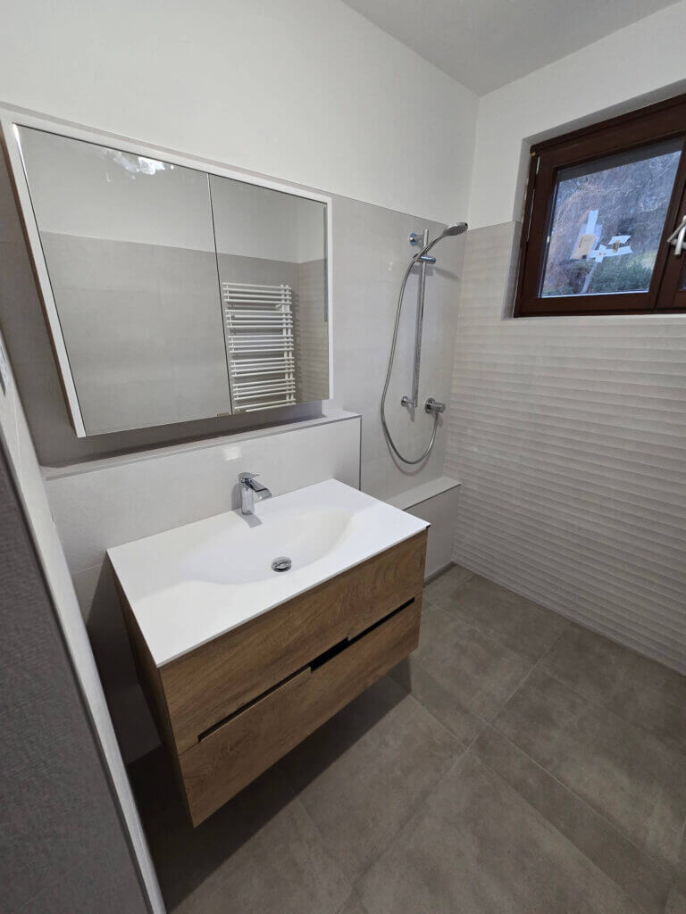 Modernes Badezimmer mit weißem Waschtisch, Spiegel und Dusche, minimalistisches Design, natürliche Holzoptik.