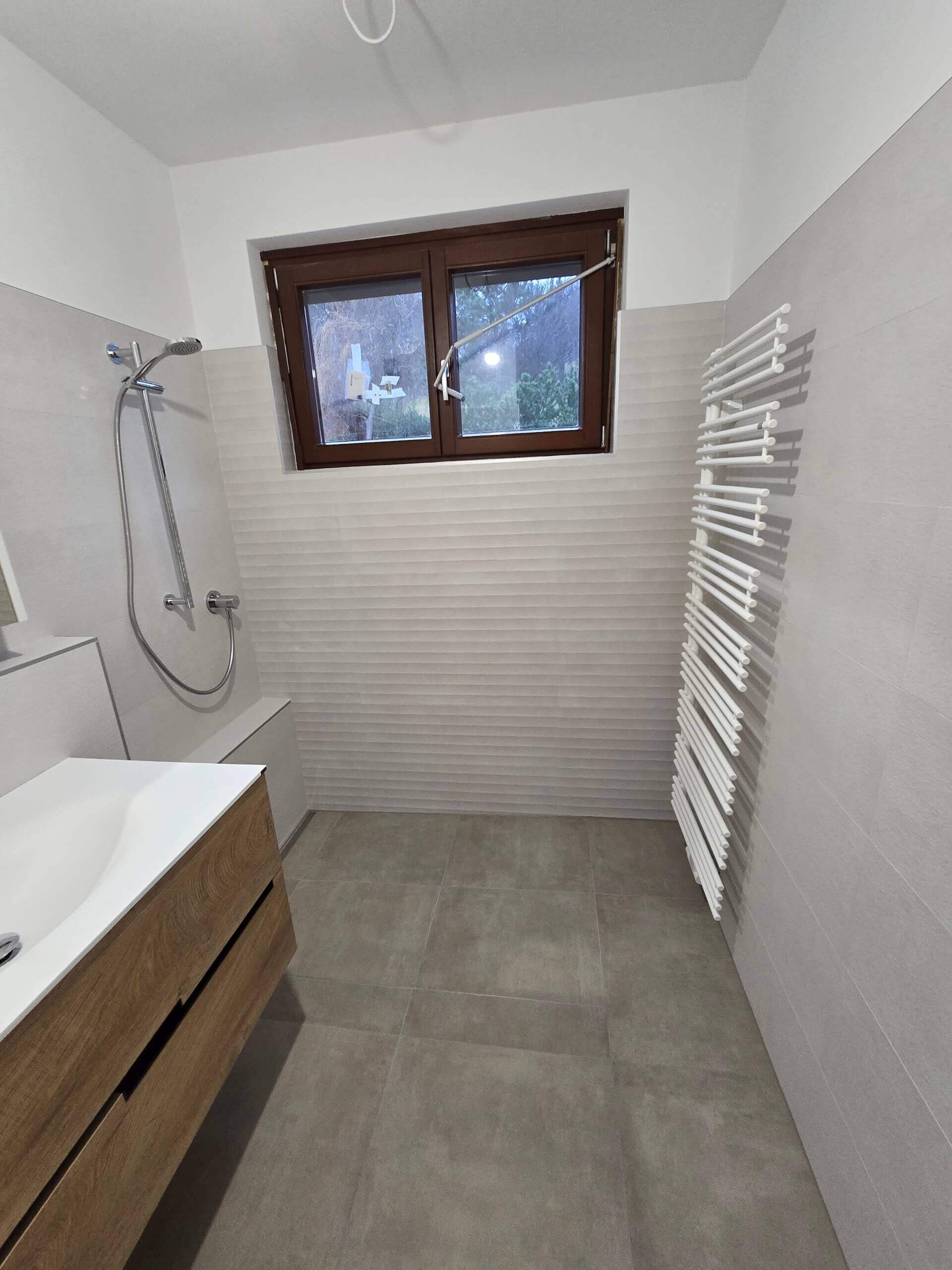 Modernes Badezimmer mit Dusche, Waschbecken und Fenster. Minimalistisches Design mit Fliesen und Handtuchheizkörper.