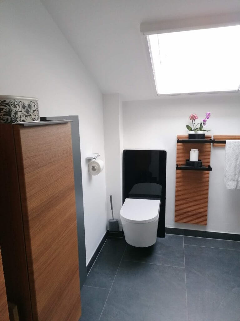 Modernes Badezimmer mit stilvollem Design, maßgeschneiderter Toilette und Holzdetails, vom Sanitärprofi renoviert.