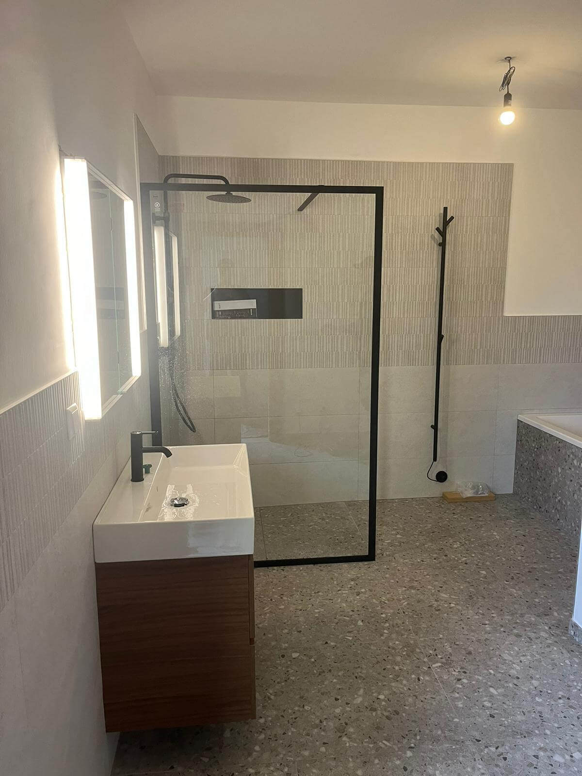 Modernes Badezimmer mit begehbarer Dusche, Holzwaschtisch und neutralen Fliesen für minimalistisches Design.