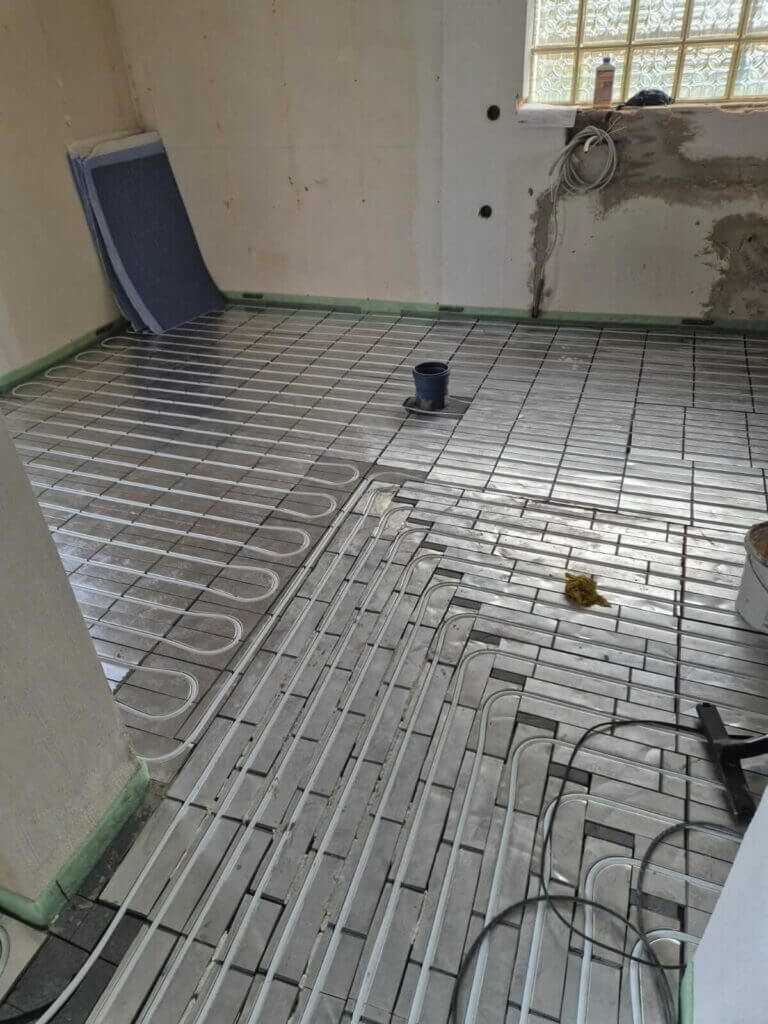 Fußbodenheizung in Renovierung: Sanitärinstallation für effiziente Wärme im Badezimmer.