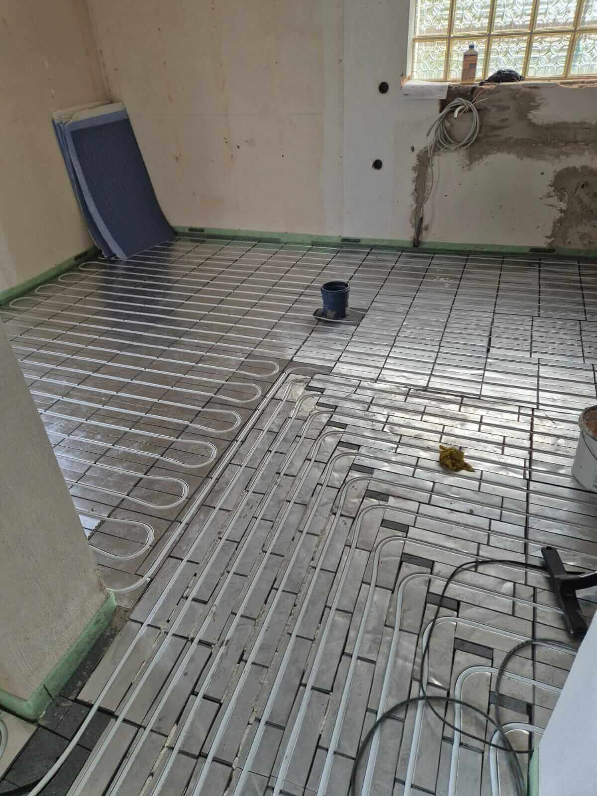 Fußbodenheizung in Renovierung: Sanitärinstallation für effiziente Wärme im Badezimmer.